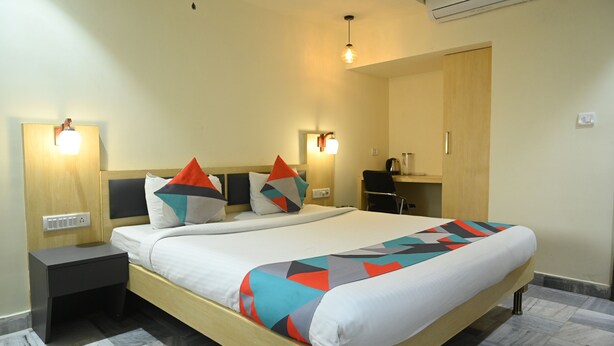 Una habitación de hotel moderna con una cama grande, dos mesitas de noche, un escritorio y un armario.