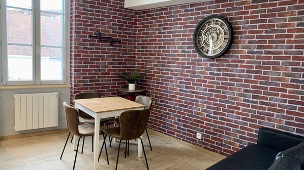 Un coin repas avec un mur en briques, une table en bois et quatre chaises.