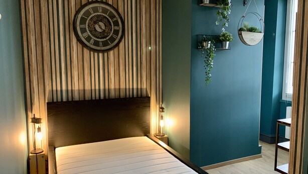 Een slaapkamer met een bed, een wandklok en een raam.