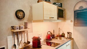 Een keuken met een houten aanrecht, een rode waterkoker, een magnetron en een kalender aan de muur.