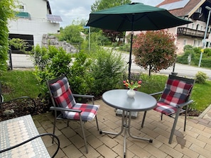 Relax in the serene patio area with a round table, comfortable chairs, and lush greenery.