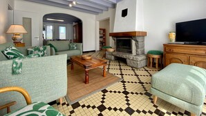 Ein Wohnzimmer mit Kamin, Sofa, Fernseher und einem gemusterten Boden.