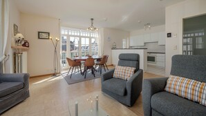 Una sala de estar moderna con un sofá gris, una mesa de comedor con sillas y una cocina al fondo.