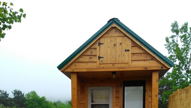A small wooden cabin with a picnic table and benches in front. - Tiny House Retreat Cabin (Freeville)