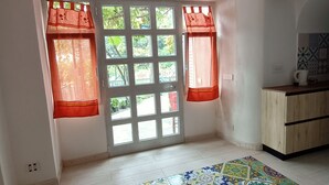 A room with a tiled floor, a window with red curtains, and a wooden cabinet. - Positano Little House. Sea view. White Dome.Terrace&WinePergola.15minToTheBeach (Positano)