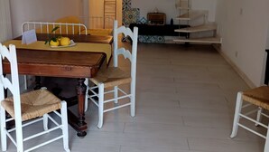 A dining area with a wooden table and white chairs, a small plant, and a yellow cushion on the table. - Positano Little House. Sea view. White Dome.Terrace&WinePergola.15minToTheBeach (Positano)