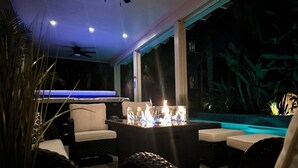 Een goed verlichte ruimte binnen met een pooltafel, comfortabele zithoek en een open haard.