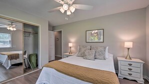 A well-lit bedroom with a large bed, two bedside tables with lamps, a ceiling fan, a wardrobe, and a mirror. - Charming Retreat on 5 Acres w/ Deck & Grill! (Browns Summit)