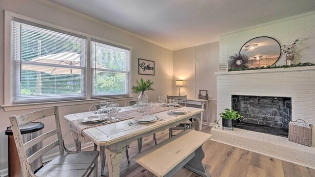 A dining area with a white brick fireplace, a table set for four, and a bench. - Charming Retreat on 5 Acres w/ Deck & Grill! (Browns Summit)