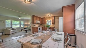 A spacious kitchen with wooden cabinets, a dining table set for six, and a large window with blinds. - Charming Retreat on 5 Acres w/ Deck & Grill! (Browns Summit)