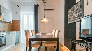 Une cuisine moderne avec un coin repas, un téléviseur et un tableau encadré au mur.