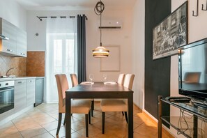 A modern kitchen with a dining area, a TV, and a framed picture on the wall.