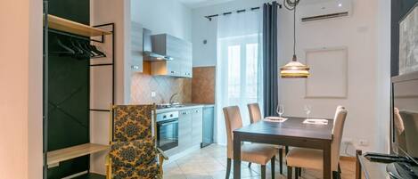 A modern kitchen with a dining area, a built-in wardrobe, and a large window.