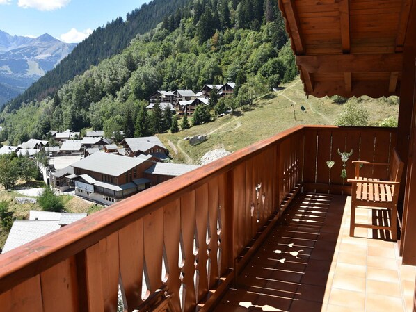 Een houten balkon met uitzicht op een bergdorp.