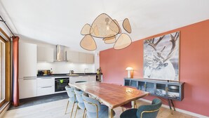 A modern kitchen with white cabinets, a wooden dining table, and a large painting of a deer on the wall.
