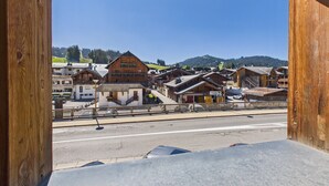 A wooden-framed window overlooking a town with traditional buildings and a clear sky.