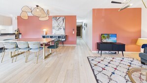 A modern living space with a dining area, kitchen, and a seating area with a television.