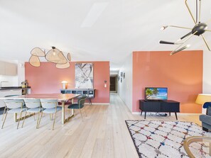 Ein zeitgemäßer Wohnraum mit Essbereich, Küche und einer Sitzecke mit Fernseher.