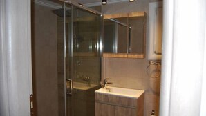 A modern bathroom with a glass-enclosed shower, a wooden vanity, and a mirror above the sink. - GTD33702 - Feel the Acropolis Apt (Athens)