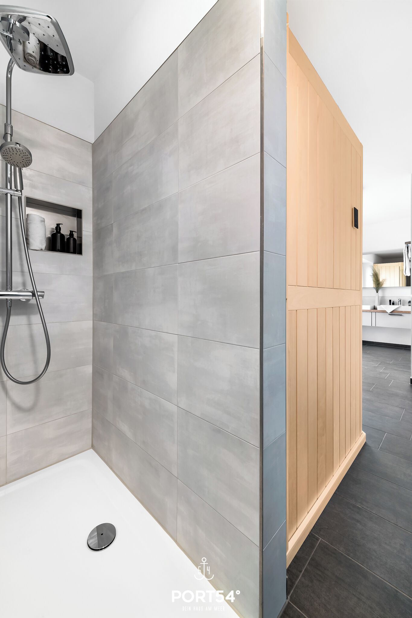 Une salle de bain moderne avec des carreaux gris, une douche et un panneau en bois.