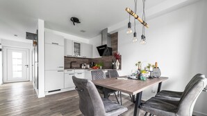 Una cucina moderna con mobili bianchi, un tavolo da pranzo in legno e sedie imbottite grigie.
