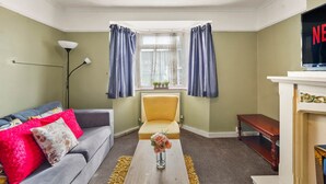 Ein Wohnzimmer mit Sofa, Sessel, Couchtisch und Kamin.