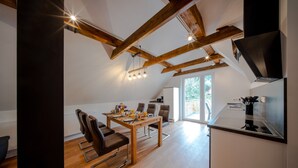 Eine moderne Küche mit Holzbalken, einem Essbereich mit Stühlen und einem großen Fenster.