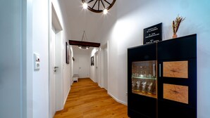 Ein Korridor mit Holzboden, weißen Wänden und einem schwarzen Schrank mit Glastüren.
