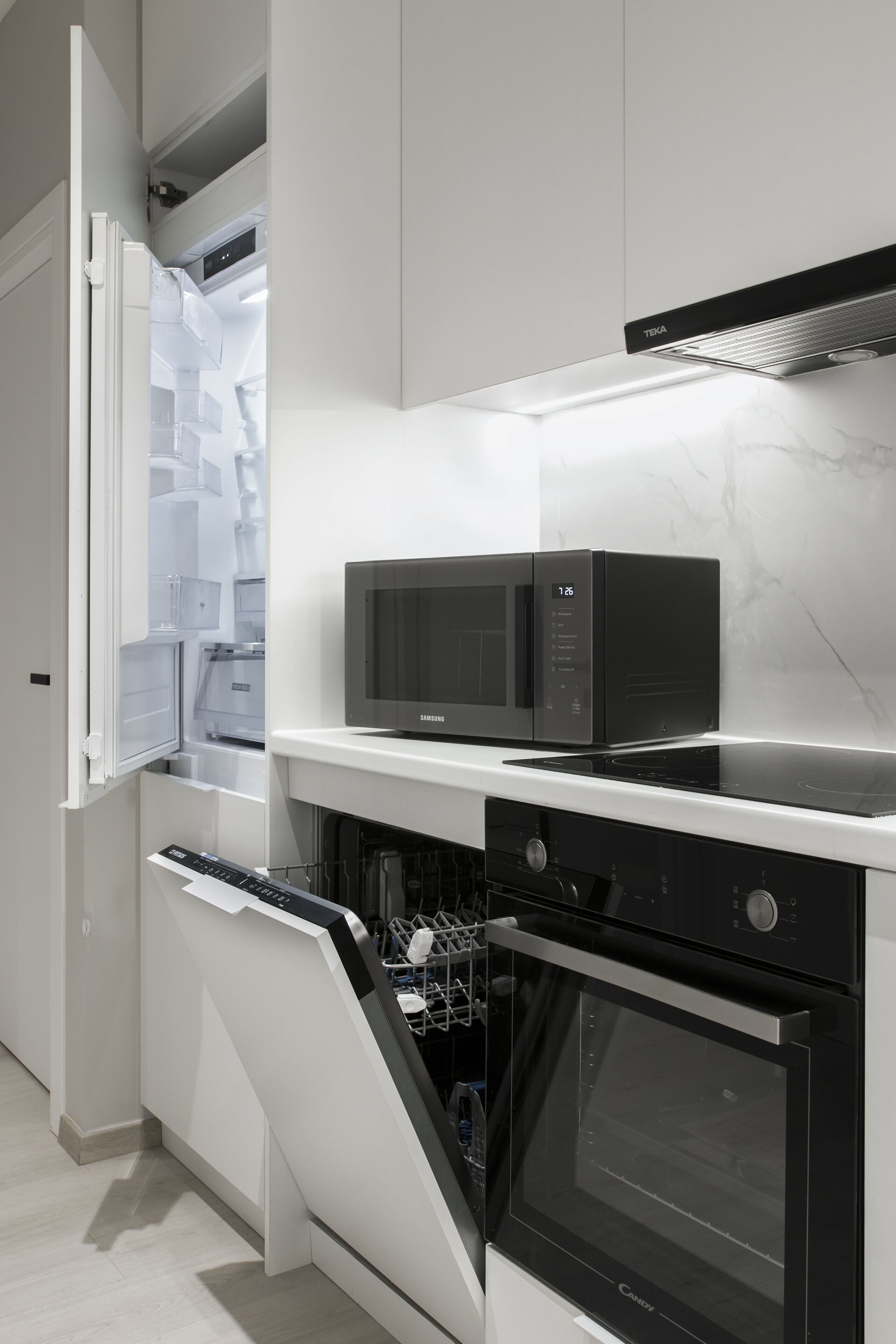 Une cuisine moderne équipée d’un four à micro-ondes, d’un four et d’un lave-vaisselle intégrés.