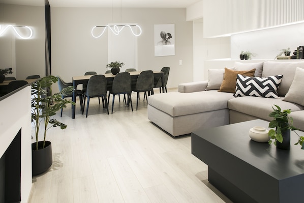 A modern living room with a sofa, a coffee table, and a dining area with chairs and a table. - Ultra Chic Modern 4 Bedrooms Apartment in Athens (Nea Smirni)