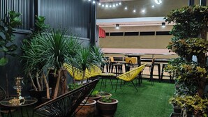 An indoor patio area with artificial grass, potted plants, and yellow chairs. - Icon Hotel Hatyai (Hat Yai)