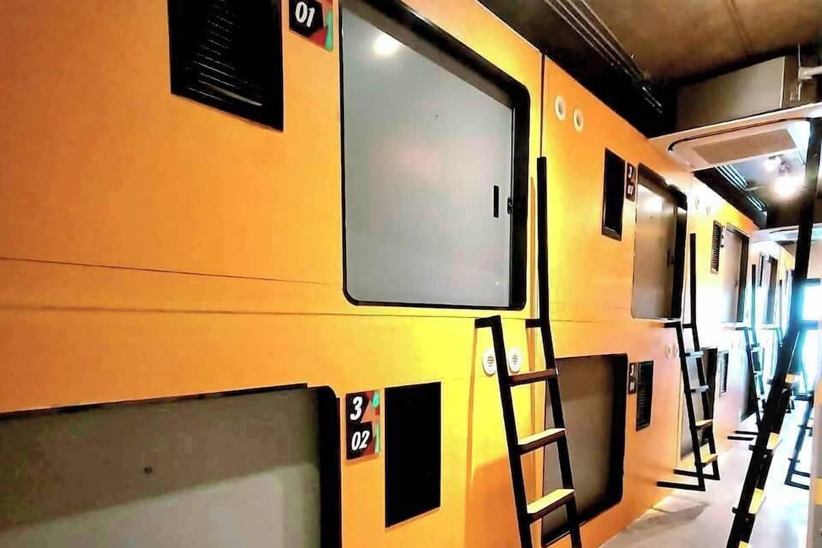 A train carriage interior with numbered compartments, a ladder, and overhead luggage racks.