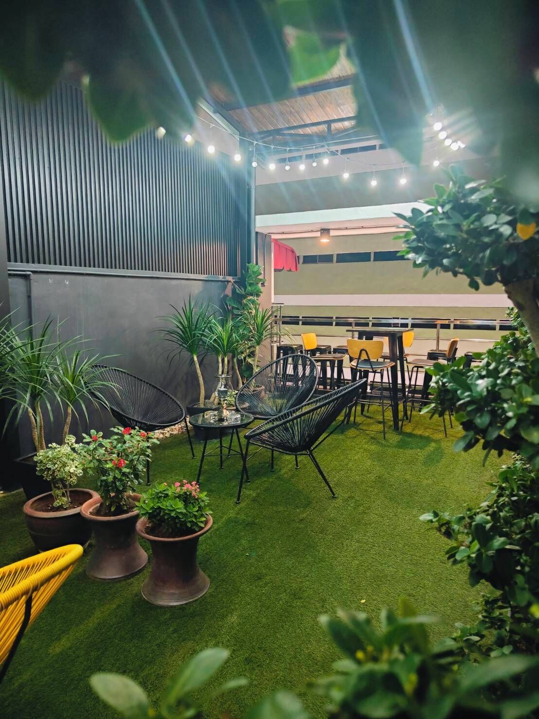 An outdoor seating area with artificial grass, potted plants, and modern furniture.