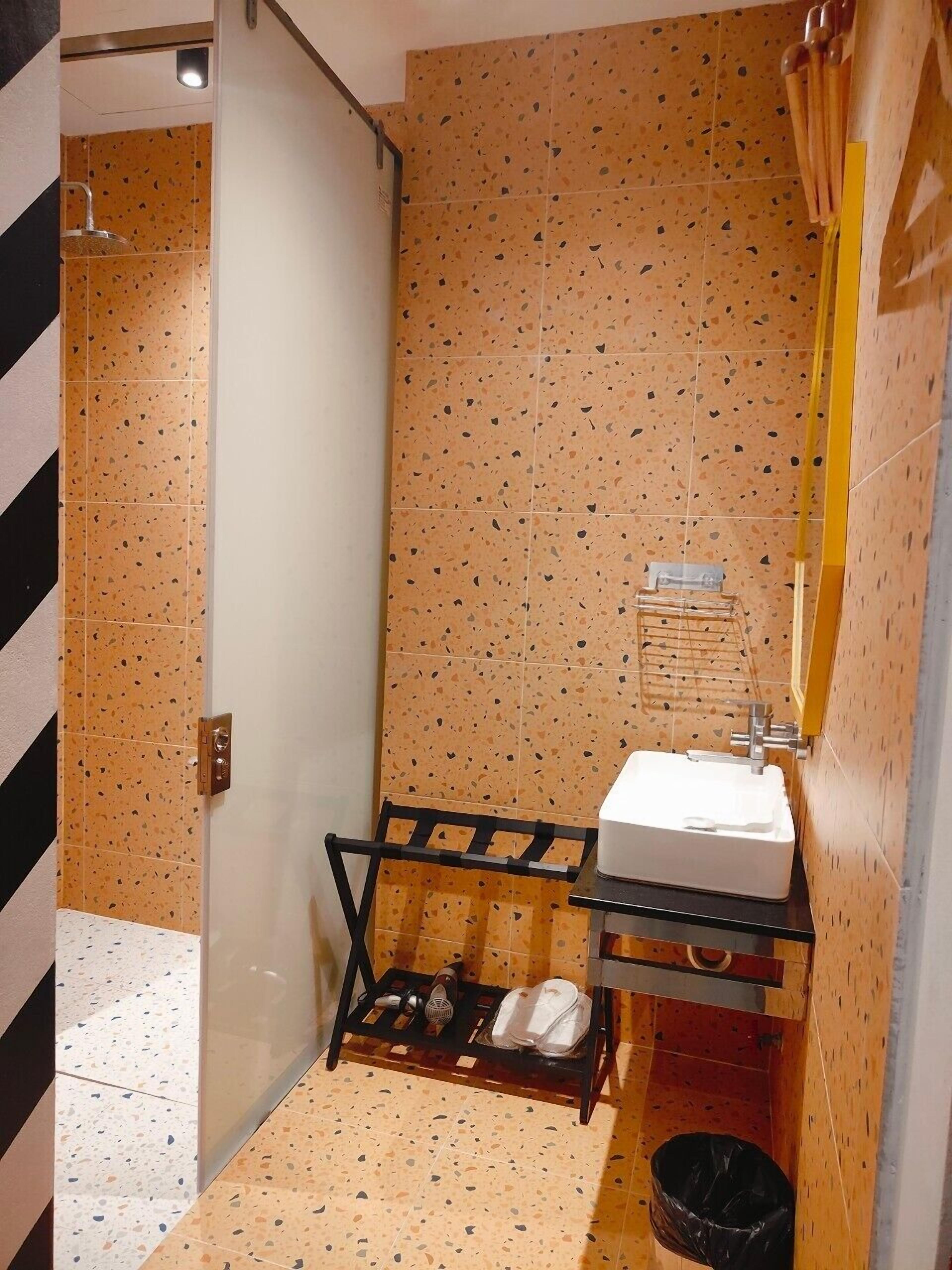 A bathroom with a shower, a sink, and a towel rack.