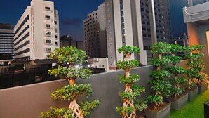 A rooftop garden with bonsai trees, surrounded by modern buildings. - Icon Hotel Hatyai (Hat Yai)