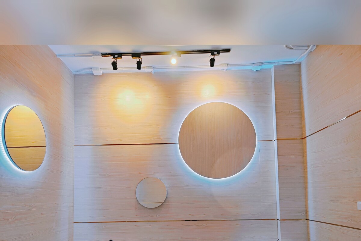 A modern room with two beds, circular wall lights, and a wooden panel design.
