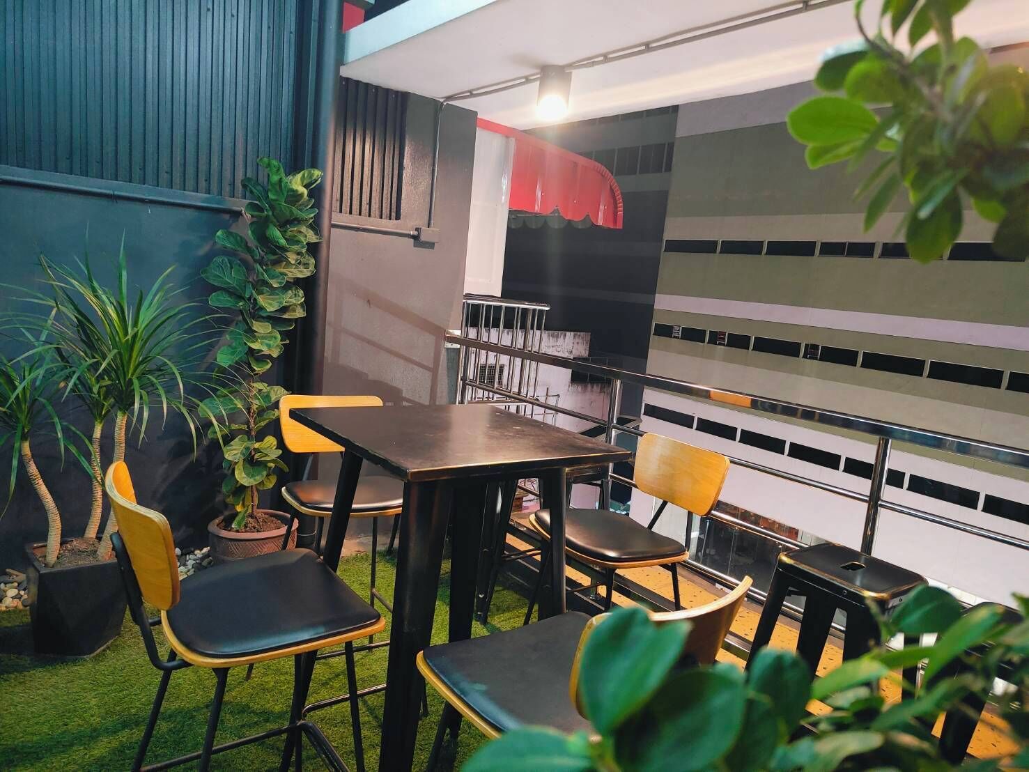 Un espace repas avec des tables et des chaises, un barbecue et des plantes en pot.
