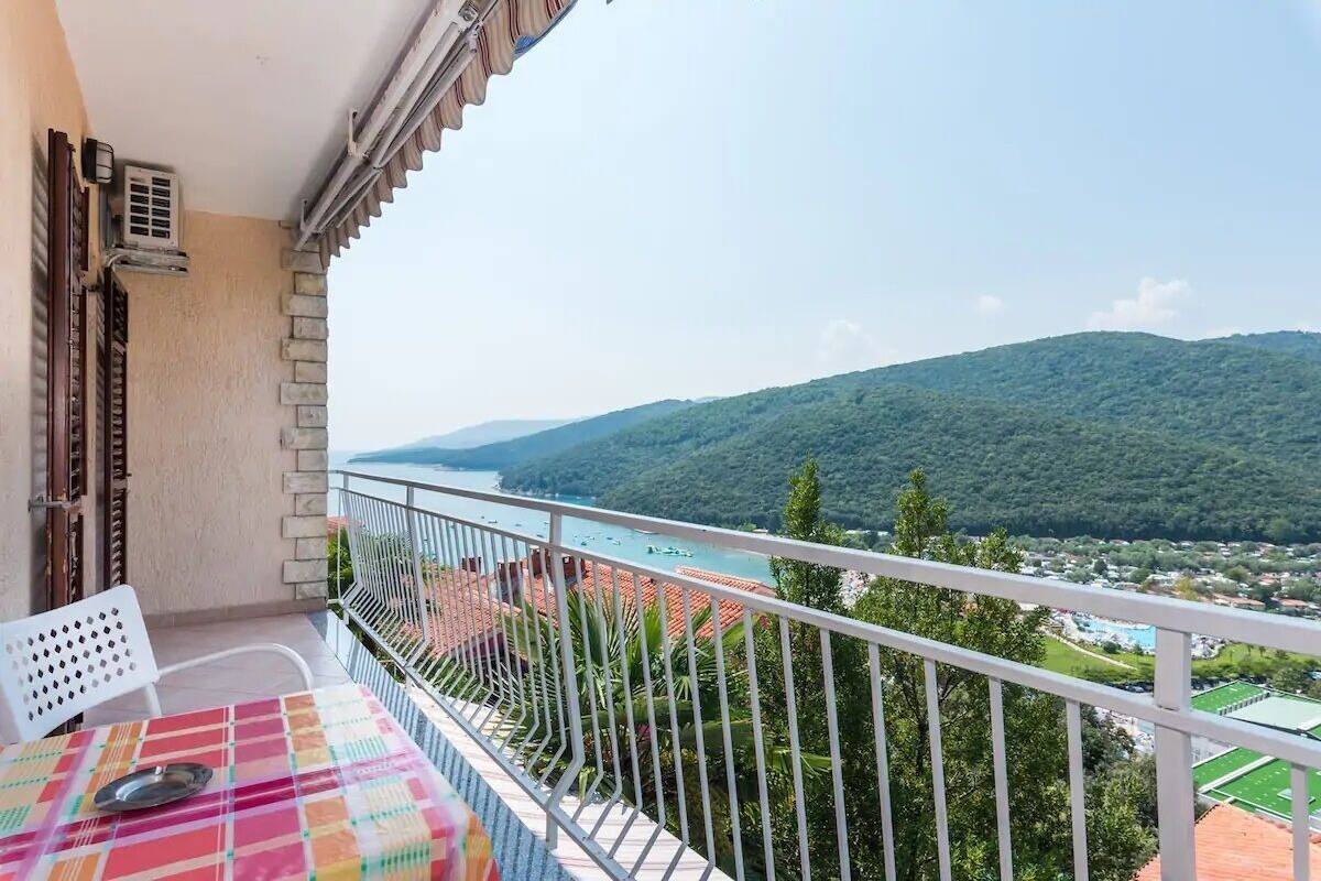 Un balcón con vistas a un pueblo costero y montañas.
