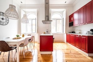 Una cocina moderna con armarios rojos, una isla blanca y luces colgantes.