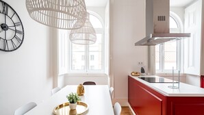 Una cucina moderna con isola bianca, mobili rossi e un'ampia finestra che garantisce luce naturale.