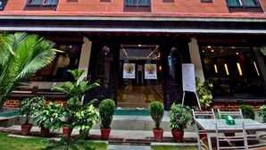 A multi-story building with a central entrance, potted plants, and a clear sky. - Hotel Kailash Kutee (Kathmandu)