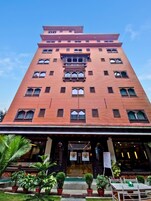Un edificio de varios pisos con una entrada central, plantas en macetas y cielo despejado.