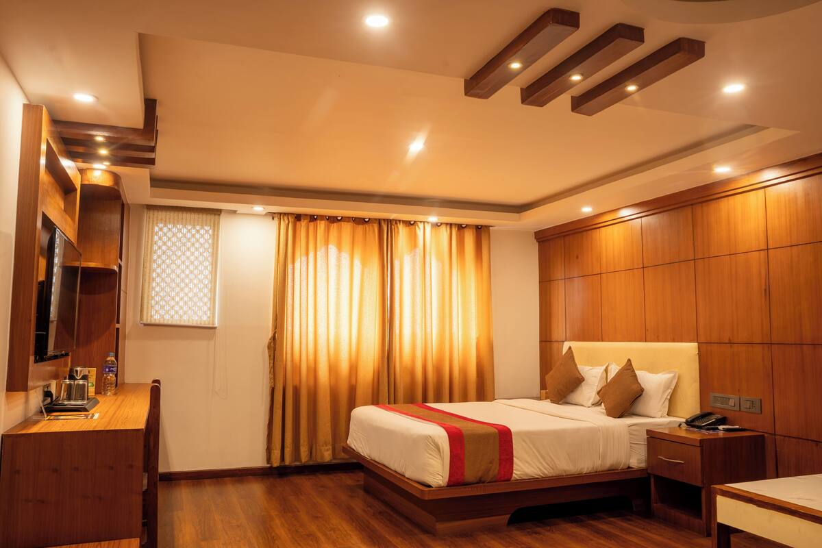 Quarto de hotel com uma cama, mesa de cabeceira e escrivaninha com uma cadeira.