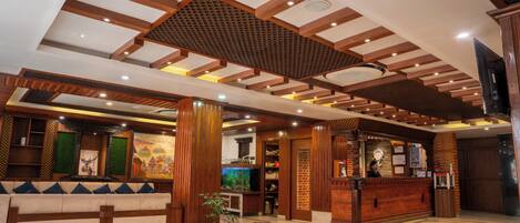 A lobby with a wooden reception desk, a seating area, and a large aquarium.