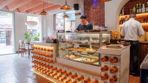 A bakery counter with a display case, a brick wall, and hanging lights. - Hotel Kailash Kutee (Kathmandu)