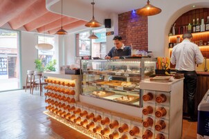 Un mostrador de panadería con una vitrina, una pared de ladrillo y luces colgantes.