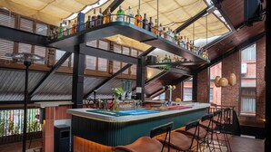 A bar area with a high ceiling, exposed brick walls, and a variety of bottles on shelves. - Hotel Kailash Kutee (Kathmandu)