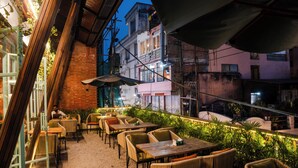 An outdoor seating area with tables and chairs, surrounded by plants and a brick wall. - Hotel Kailash Kutee (Kathmandu)