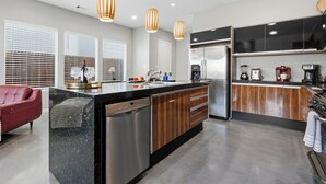 Une cuisine moderne dotée d’un îlot central, d’appareils électroménagers en acier inoxydable et de meubles de rangement en bois.