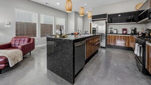 Une cuisine moderne dotée d’un îlot central, de meubles de couleur noire et d’appareils électroménagers en acier inoxydable.